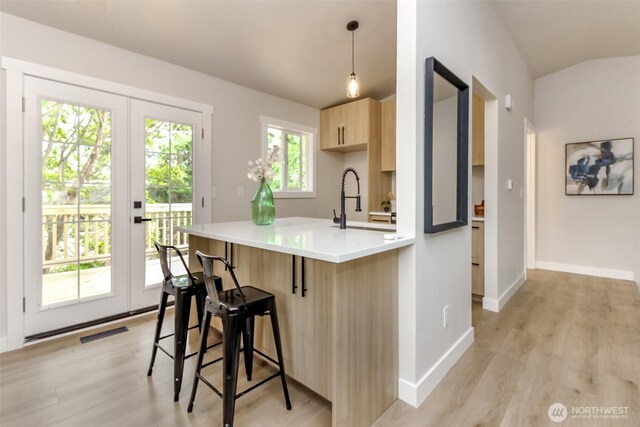 21241 S 29th Ave, Seatac, WA 98198 - kitchen featuring light brown cabinetry, french doors, light wood finished floors, and a kitchen breakfast bar