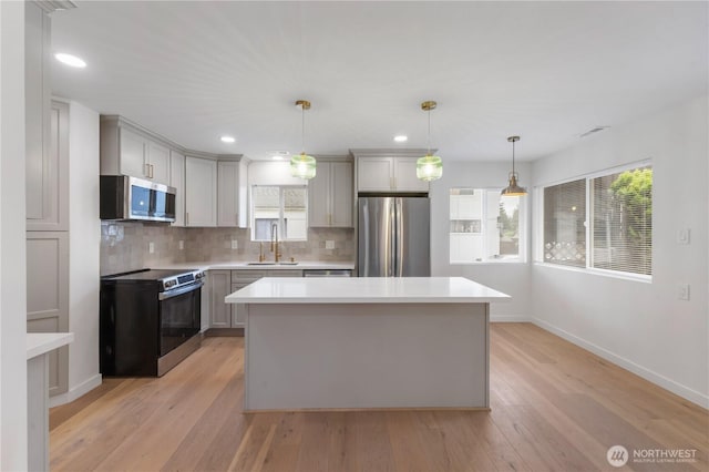 10303 40th Ave E, Tacoma, WA 98446 - kitchen with appliances with stainless steel finishes, decorative backsplash, light wood-style flooring, light countertops, and a center island