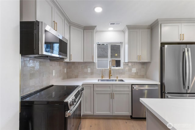 10303 40th Ave E, Tacoma, WA 98446 - kitchen with stainless steel appliances, light countertops, light wood-type flooring, backsplash, and recessed lighting