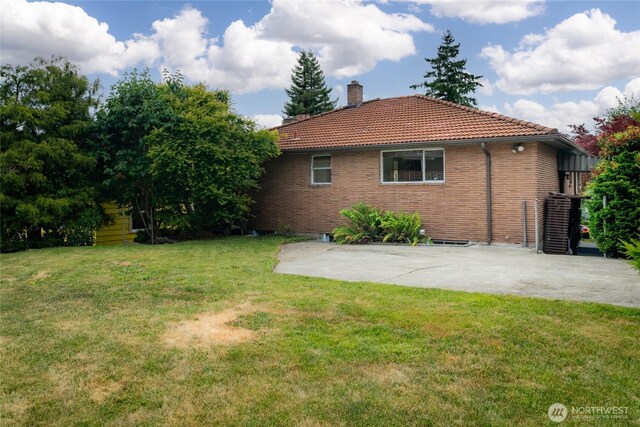 2842 NW 67th St, Seattle, WA 98117 - view of property exterior with a chimney, a tiled roof, a lawn, a patio, and brick siding