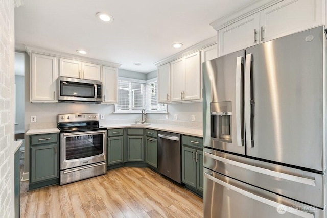 4431 SW Kenyon Pl, Seattle, WA 98136 - kitchen featuring appliances with stainless steel finishes, green cabinetry, light countertops, light wood-style flooring, and white cabinets