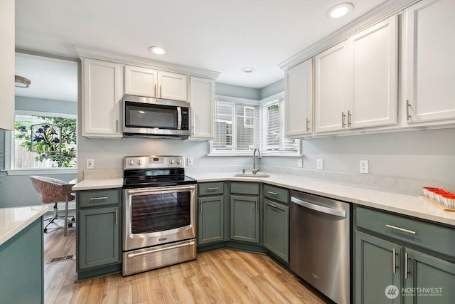 4431 SW Kenyon Pl, Seattle, WA 98136 - kitchen featuring appliances with stainless steel finishes, green cabinetry, light countertops, white cabinetry, and recessed lighting