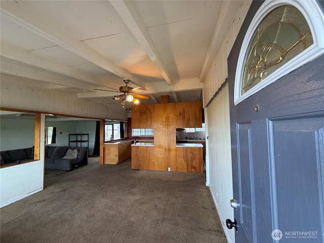 1309 29th St, Anacortes, WA 98221 - kitchen with brown cabinets, dark colored carpet, a ceiling fan, wood walls, and beam ceiling