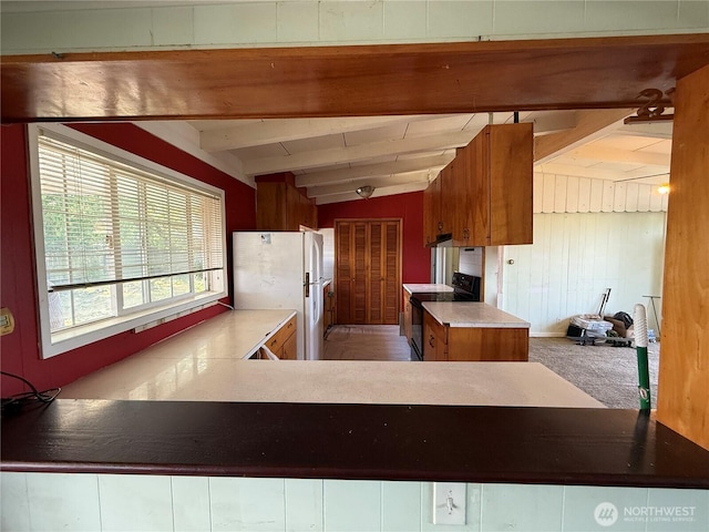 1309 29th St, Anacortes, WA 98221 - kitchen with black range with electric cooktop, freestanding refrigerator, beamed ceiling, brown cabinets, and a peninsula