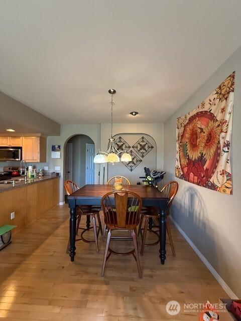 2103 Tacoma Ct, Tacoma, WA 98405 - dining area with arched walkways, light wood-type flooring, and a chandelier