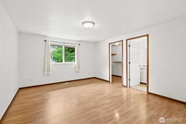 7609 39th Ct SE, Lacey, WA 98503 - unfurnished bedroom with light wood-style flooring, a walk in closet, a closet, and a textured ceiling