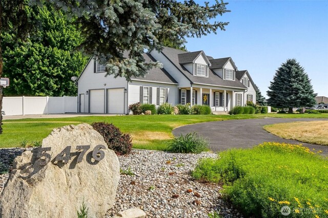 5476 Lorri Ln, Moses Lake, WA 98837 - cape cod-style house with driveway, a garage, and covered porch