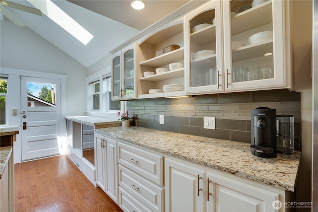5111 N 39th St, Tacoma, WA 98407 - kitchen with a skylight, light wood-style flooring, glass insert cabinets, decorative backsplash, and high vaulted ceiling
