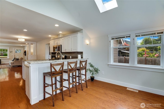 5111 N 39th St, Tacoma, WA 98407 - kitchen featuring stainless steel microwave, plenty of natural light, white cabinets, a peninsula, and recessed lighting