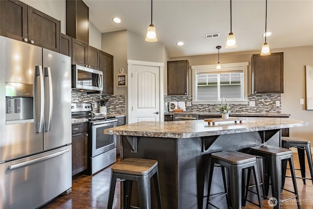 406 Harrison Ln, Nooksack, WA 98276 - kitchen featuring appliances with stainless steel finishes, dark brown cabinetry, a breakfast bar area, dark wood-style flooring, and recessed lighting