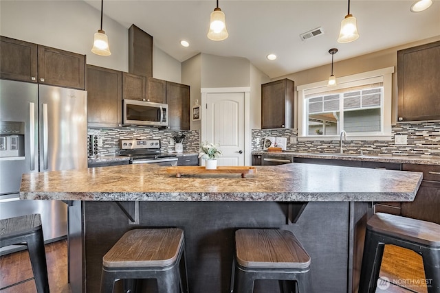 406 Harrison Ln, Nooksack, WA 98276 - kitchen featuring stainless steel appliances, dark brown cabinets, backsplash, lofted ceiling, and pendant lighting