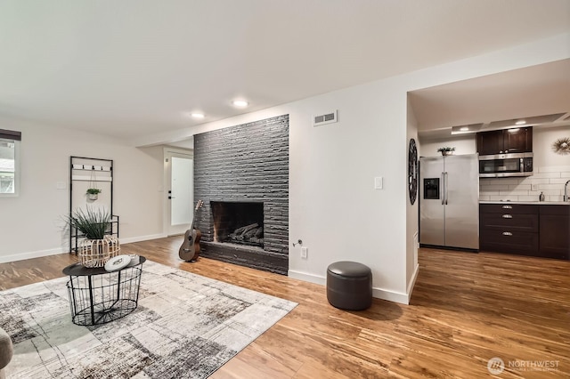 11446 Ohde Ave, Kirkland, WA 98033 - living area with a large fireplace, wood finished floors, and recessed lighting