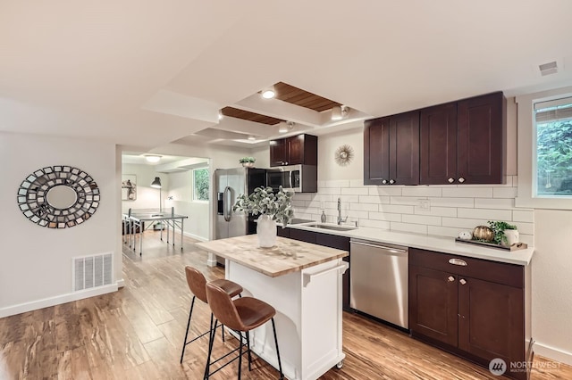 11446 Ohde Ave, Kirkland, WA 98033 - kitchen featuring appliances with stainless steel finishes, a kitchen bar, light countertops, dark brown cabinetry, and backsplash