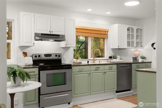 15516 10th Ave NE, Shoreline, WA 98155 - kitchen with under cabinet range hood, stainless steel appliances, green cabinets, decorative backsplash, and white cabinetry