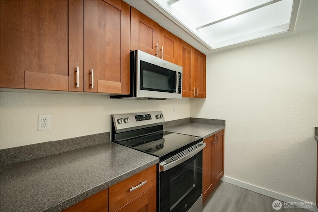 12617 NE 130th Way Unit E303, Kirkland, WA 98034 - kitchen featuring appliances with stainless steel finishes, dark countertops, wood finished floors, and brown cabinets