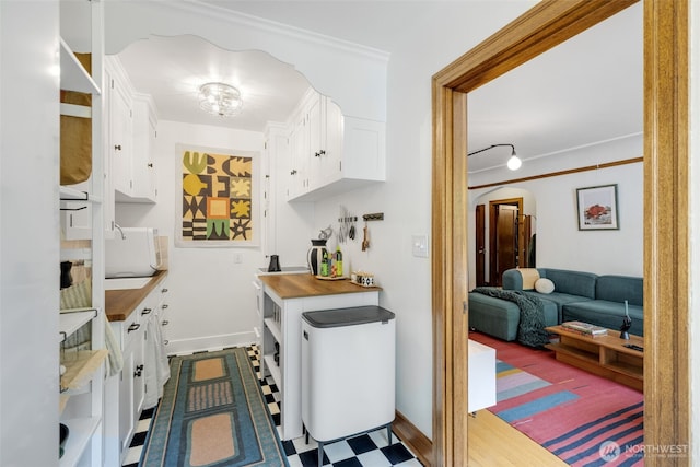 1631 16th Ave Unit 114, Seattle, WA 98122 - kitchen featuring white cabinetry, crown molding, white microwave, and arched walkways