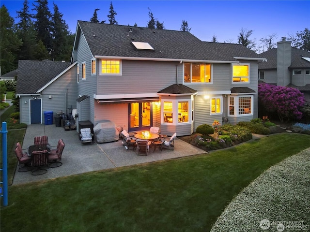 2601 59th St SW, Everett, WA 98203 - back of house at dusk with a shingled roof, a lawn, a patio, and an outdoor fire pit