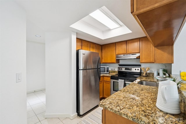 10004 100th Ave NE Unit K202, Kirkland, WA 98034 - kitchen with stainless steel appliances, under cabinet range hood, brown cabinetry, light stone counters, and recessed lighting