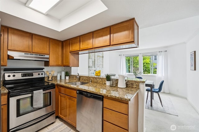 10004 100th Ave NE Unit K202, Kirkland, WA 98034 - kitchen featuring appliances with stainless steel finishes, under cabinet range hood, brown cabinets, a peninsula, and light stone counters