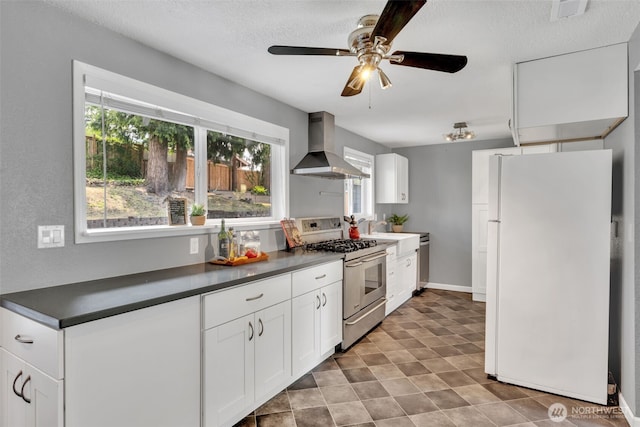 16318 128th Pl SE, Renton, WA 98058 - kitchen featuring stainless steel appliances, wall chimney exhaust hood, dark countertops, a ceiling fan, and white cabinets