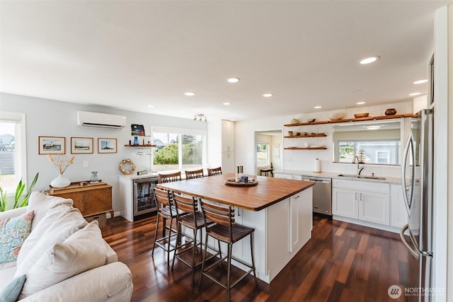 4452 Saltspring Dr, Ferndale, WA 98248 - kitchen with appliances with stainless steel finishes, butcher block countertops, open shelves, an AC wall unit, and white cabinets