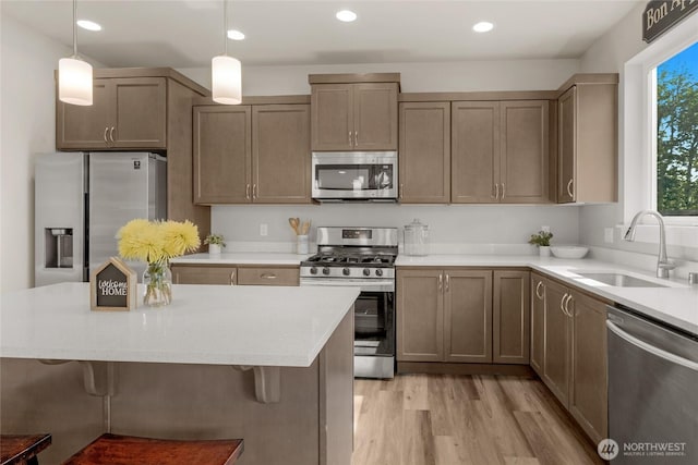 803 Loves Hill Dr, Sultan, WA 98294 - kitchen with stainless steel appliances, a breakfast bar, light wood-type flooring, decorative light fixtures, and recessed lighting