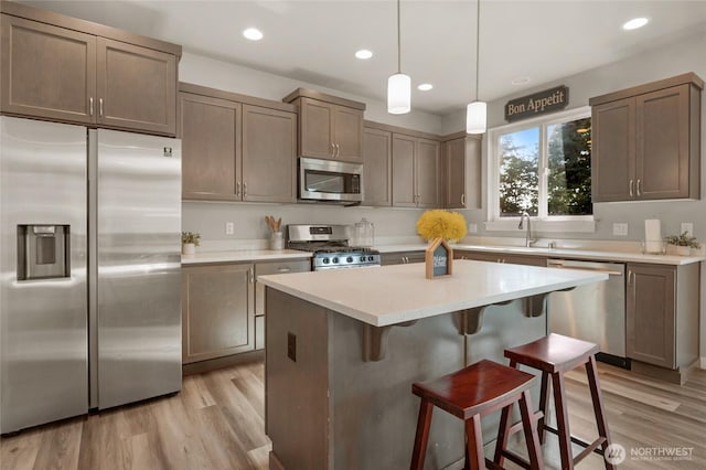 803 Loves Hill Dr, Sultan, WA 98294 - kitchen featuring appliances with stainless steel finishes, light wood finished floors, a breakfast bar area, a kitchen island, and light countertops