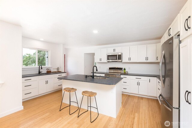 150 Sunland Dr, Sequim, WA 98382 - kitchen with appliances with stainless steel finishes, dark countertops, light wood-style flooring, white cabinetry, and recessed lighting