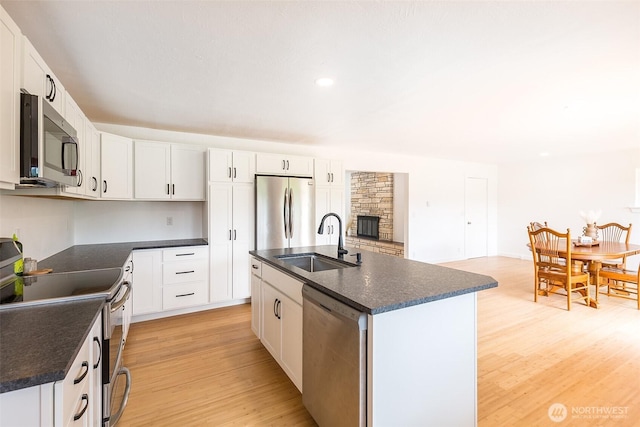 150 Sunland Dr, Sequim, WA 98382 - kitchen with appliances with stainless steel finishes, dark countertops, light wood-style floors, a center island with sink, and white cabinetry