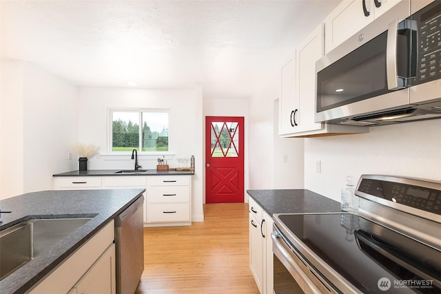 150 Sunland Dr, Sequim, WA 98382 - kitchen featuring stainless steel appliances, light wood-style flooring, white cabinetry, and dark stone counters