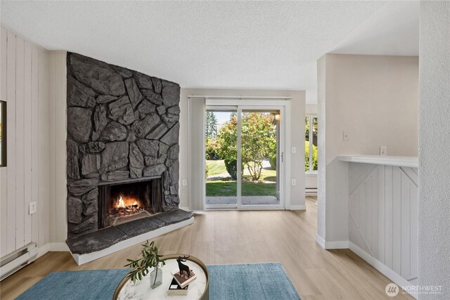 4709 176th St SW Unit C1, Lynnwood, WA 98037 - living area featuring wood finished floors, baseboard heating, a stone fireplace, and a textured ceiling