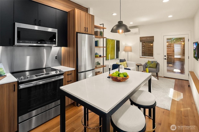 3626 1st Ave NW Unit A, Seattle, WA 98107 - kitchen with stainless steel appliances, light countertops, light wood-style floors, open shelves, and pendant lighting