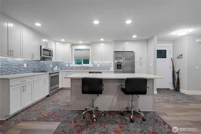 11108 Pilchuck Ct SE, Olympia, WA 98501 - kitchen with appliances with stainless steel finishes, tasteful backsplash, a kitchen bar, a center island, and light wood finished floors