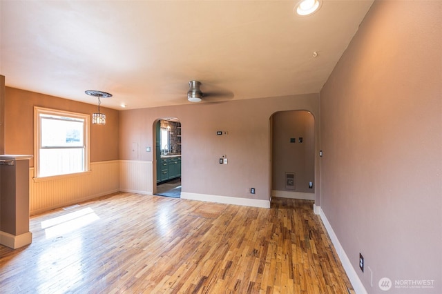 218 125th St S, Tacoma, WA 98444 - unfurnished room featuring arched walkways, light wood finished floors, a wainscoted wall, and a ceiling fan