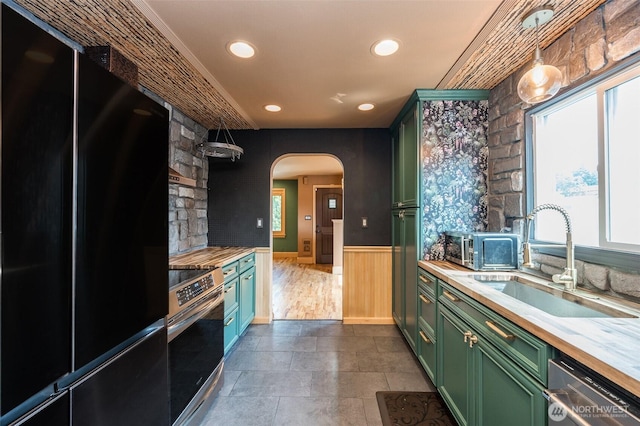 218 125th St S, Tacoma, WA 98444 - kitchen with green cabinets, stainless steel appliances, healthy amount of natural light, arched walkways, and wainscoting