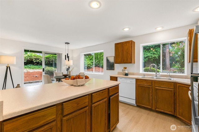 20039 99th Ct NE, Bothell, WA 98011 - kitchen featuring white dishwasher, brown cabinetry, light countertops, light wood-type flooring, and hanging light fixtures