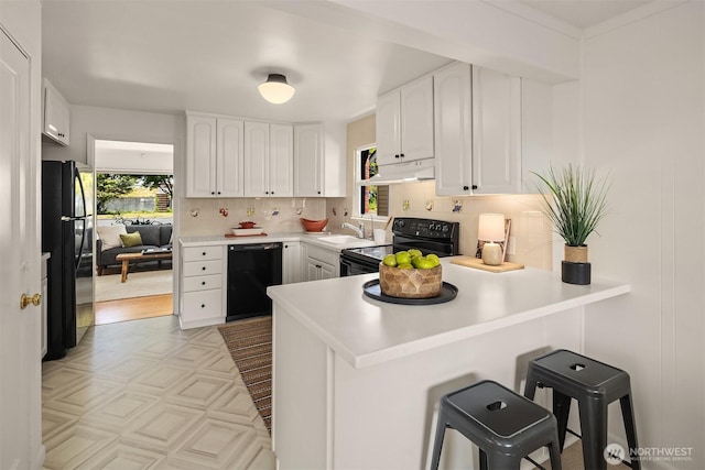6045 36th Ave SW, Seattle, WA 98126 - kitchen with black appliances, under cabinet range hood, a peninsula, white cabinets, and decorative backsplash