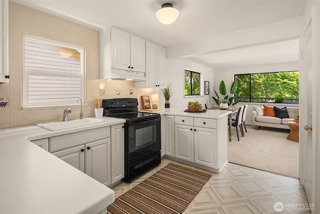 6045 36th Ave SW, Seattle, WA 98126 - kitchen featuring black range with electric stovetop, under cabinet range hood, white cabinets, a peninsula, and light countertops