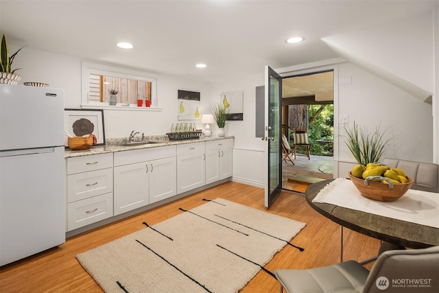 6045 36th Ave SW, Seattle, WA 98126 - kitchen featuring freestanding refrigerator, light wood finished floors, white cabinets, recessed lighting, and light stone counters