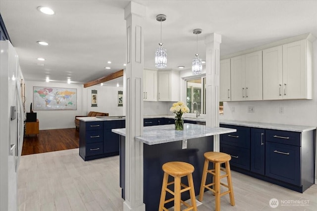 18020 SE 146th St, Renton, WA 98059 - kitchen featuring blue cabinetry, white cabinetry, a center island, a kitchen bar, and light wood-type flooring