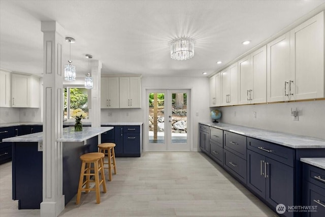 18020 SE 146th St, Renton, WA 98059 - kitchen with a kitchen breakfast bar, blue cabinets, light wood-style floors, decorative light fixtures, and white cabinetry