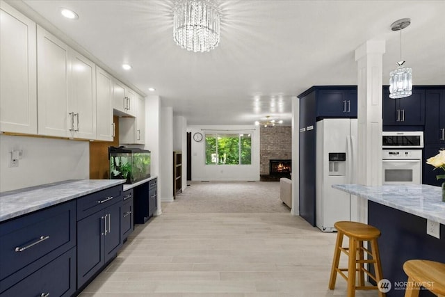 18020 SE 146th St, Renton, WA 98059 - kitchen with white appliances, a chandelier, a fireplace, a kitchen bar, and recessed lighting