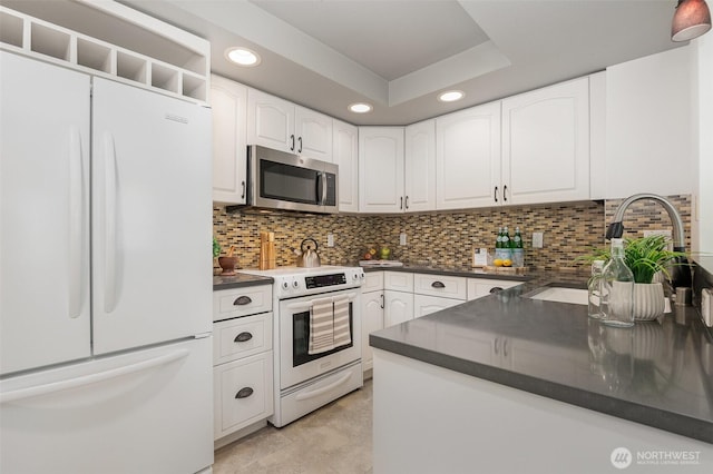 11011 NE 12th St Unit 501, Bellevue, WA 98004 - kitchen with white appliances, dark countertops, recessed lighting, white cabinets, and tasteful backsplash