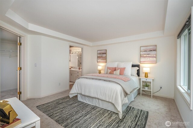 11011 NE 12th St Unit 501, Bellevue, WA 98004 - bedroom featuring light colored carpet, a raised ceiling, ensuite bath, and a walk in closet