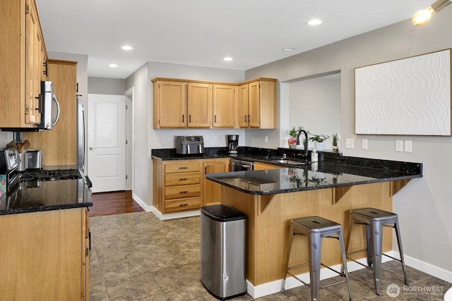8419 Double Ditch Rd, Lynden, WA 98264 - kitchen featuring appliances with stainless steel finishes, a peninsula, dark stone countertops, a kitchen breakfast bar, and recessed lighting