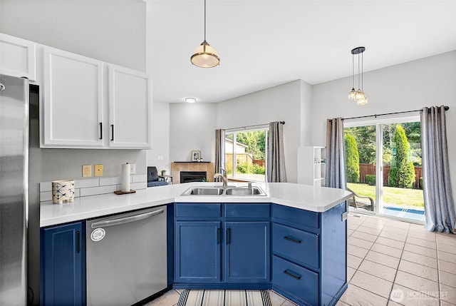209 Groff Ave NW, Orting, WA 98360 - kitchen with appliances with stainless steel finishes, a peninsula, blue cabinets, white cabinetry, and a tiled fireplace