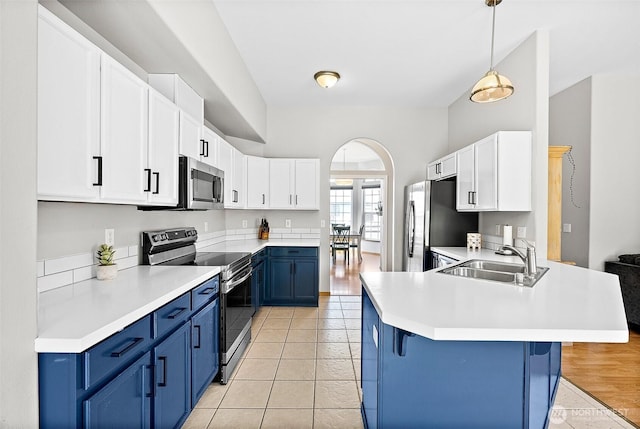 209 Groff Ave NW, Orting, WA 98360 - kitchen featuring stainless steel appliances, blue cabinets, a peninsula, a kitchen bar, and light countertops