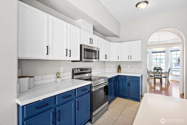 209 Groff Ave NW, Orting, WA 98360 - kitchen with appliances with stainless steel finishes, blue cabinets, white cabinets, light countertops, and light tile patterned floors
