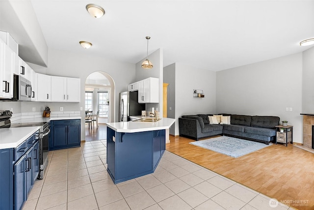 209 Groff Ave NW, Orting, WA 98360 - kitchen featuring blue cabinetry, appliances with stainless steel finishes, a peninsula, open floor plan, and light tile patterned floors