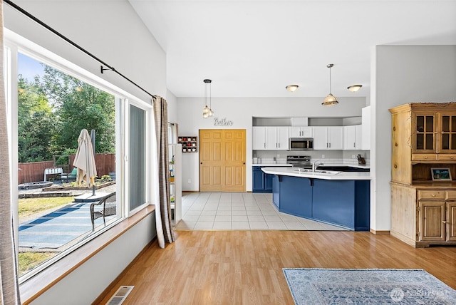209 Groff Ave NW, Orting, WA 98360 - kitchen featuring stainless steel microwave, a breakfast bar, light wood-type flooring, light countertops, and white cabinets